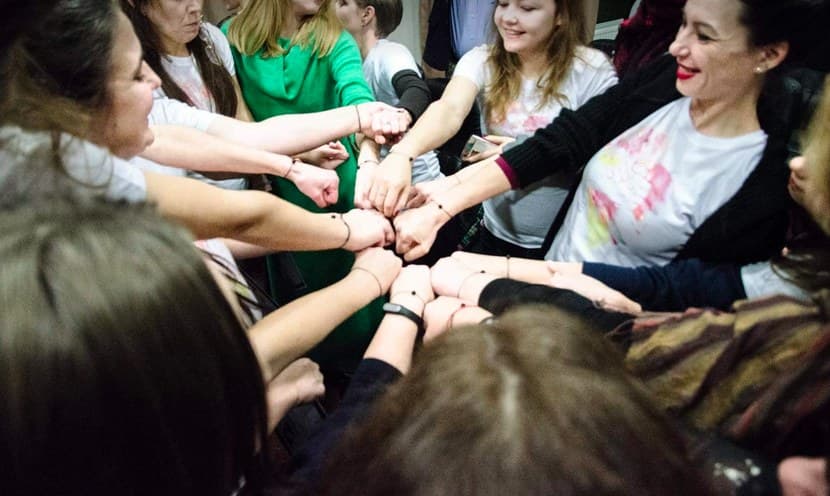 Women in a training group join their hands in the middle of a circle.