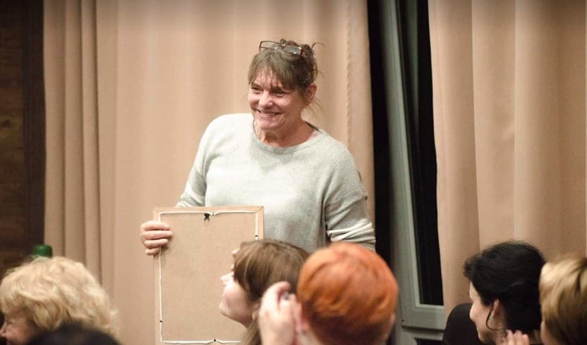 Ditte Marcher smiles at a group of participants, holding an empty picture frame used in an exercise.
